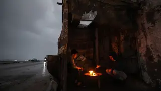 Refugiados palestinos entran en calor junto al fuego durante un frío día de invierno en el campo de refugiados de Al Shati, en Franja de Gaza, el 19 de enero.