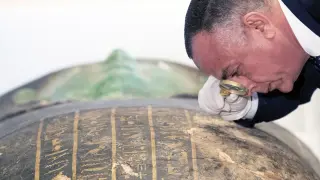 Un experto examina el estado del Sarcófago Verde, que Estados Unidos ha devuelto a Egipto.