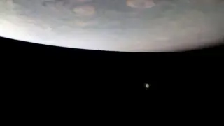 Júpiter aparece sobre dos de sus mayores lunas, captadas en la lejanía.