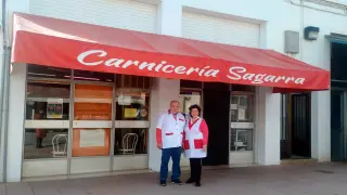 Primitivo Sagarra y Elena Bruned, el matrimonio que lleva la carnicería con la ayuda de sus hijos, ante su negocio.