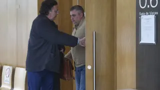 El guardia civil condenado por abusos, con chaqueta marrón, saliendo de la sala de vistas de la Audiencia de Huesca con su abogado.