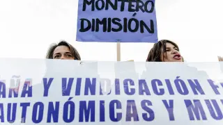 Dos manifestantes en Madrid sostienen una pancarta en la que piden la dimisión de Irene Montero