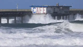 Olas chocan contra un muelle del océano en la costa de San Diego, California