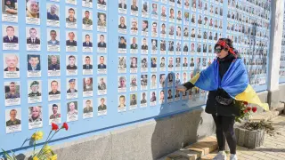 Una mujer mira las imágenes de los soldados ucranianos caídos en combate