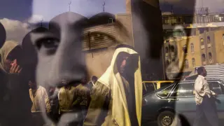personas que caminan por la calle Rasheed se reflejan en un retrato en blanco y negro del presidente iraquí Saddam Hussein en Bagdad IRAQ PHOTO SET INVASION 20TH ANNIVERSARY