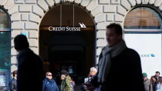 People walk near the logo of the Swiss bank Credit Suisse in Zurich
