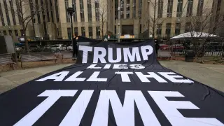 Manifestantes anti-Trump sostienen una pancarta en un parque cerca del Tribunal Penal de Manhattan