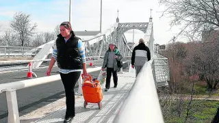 Tres personas atraviesan uno de los puentes después de los trabajos de rehabilitación