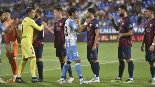Los jugadores del Huesca y el Málaga se saludan al inicio del partido de la primera vuelta.