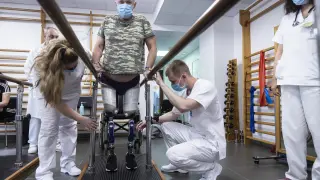 La médico rehabilitadora Valentina Shevets y el fisioterapeuta Illia Hrytsuik, ayudan al herido militar ucraniano Alexander en el Hospital Militar.