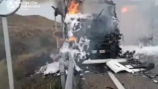 Los bomberos sofocan el fuego producido tras la colisión entre dos camiones