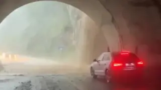 Un conductor detenido en un túnel mientras la tromba de agua cae en la entrada como una cascada.