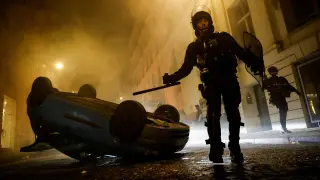 Policías antidisturbios franceses caminan junto a un vehículo durante el quinto día de protestas tras la muerte de Nahel