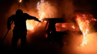 Un bombero francés trabaja para extinguir un automóvil en llamas durante el quinto día de protestas tras la muerte de Nahel