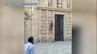 Un hombre se encarama a la fachada de la Puerta Santa en la catedral de Santiago