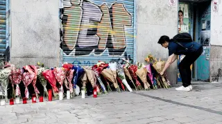 Una mujer deja un ramo de flores en la puerta de la tienda donde fue asesinada Concha