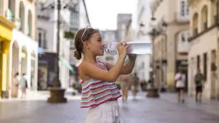 Una niña bebiendo agua en la calle Alfonso I de Zaragoza.