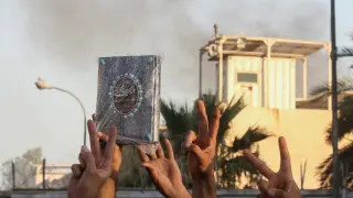 A protester holds up a Koran as smoke rises from the Swedish embassy building as protesters gather near the embassy in Baghdad hours after it was stormed and set on fire ahead of an expected Koran burning in Stockholm, in Baghdad, Iraq, July 20, 2023. REUTERS/Ahmed Saad REFILE - QUALITY REPEAT