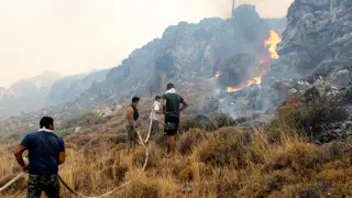 Kiotari (Greece), 22/07/2023.- Volunteers try to put out a wildfire in Kiotari village, on Rhodes island, Greece 22 July 2023. Although the Fire Department had managed to put out several rekindled blazes on the island over the last few days, the wildfire near the village of Laerma in the island's north keeps expanding and moving eastwards to the Gadoura dam, while residents in the villages of Lardos and Pilonas were told to evacuated their homes on the day, via the emergency number 112. Some 173 firefighters with 35 fire engines and 10 ground teams are battling the blaze, assisted by 3 water bombers and 2 helicopters. Another 31 firefighters with 4 fire engines and 3 ground teams were also expected to arrive from Slovakia. Local authority water tanks are also helping out. (incendio forestal, Grecia, Eslovaquia) EFE/EPA/DAMIANIDIS LEFTERIS