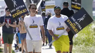 Zach Braff, left, and Donald Faison walk on a picket line outside Netflix studios on Tuesday, July 25, 2023, in Los Angeles. The actors strike comes more than two months after screenwriters began striking in their bid to get better pay and working conditions. (AP Photo/Chris Pizzello)