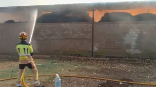 Un bombero apaga el fuego declarado en un almacén de paja en La Ginebrosa.
