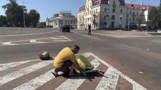 Un hombre, junto al cuerpo cubierto de una de las víctimas mortales del ataque ruso a la plaza de la ciudad ucraniana de Chernígov