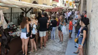 Los visitantes y vecinos del pueblo observan los puestos que conforman el mercado medieval.