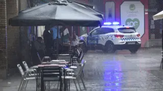 Varias personas se protegen de la lluvia en una terraza en Huesca, este sábado.