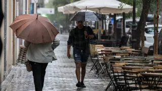 Varias personas se resguardan de la lluvia con paraguas, en Madrid (España).