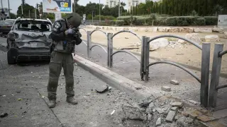 Un policía israelí toma fotografías de una carretera dañada por un ataque con cohetes, en Ashkelon, al sur de Israel.