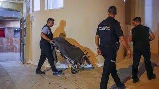 Traslado de uno de los cuerpos en la entrada del edificio donde han sido encontrados los cadáveres de un hombre y una mujer en Torrequemada, Benalmádena.