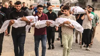 Un grupo de hombres sostiene los cuerpos sin vida de tres pequeños en Gaza