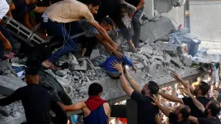 Ciudadanos palestinos rescatan a dos niños entre los escombros de un edificio en Gaza