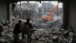 Dos hombres observan los trabajos de desescombro tras un bombardeo en Gaza