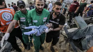 Los palestinos cargan a una niña herida después de recuperarla de los escombros de una zona destruida tras los ataques aéreos israelíes en la ciudad de Gaza