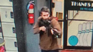 A man identified as a suspect by police points what appears to be a semiautomatic rifle, in Lewiston