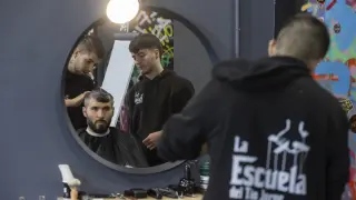 Un alumno corta el pelo a un cliente.