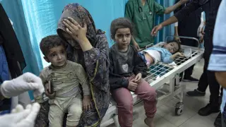 Una mujer y sus dos hijos esperan ser atendidos en un hospital en Gaza tras resultar heridos en un bombardeo de Israel, este domingo.