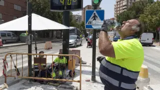 Un trabajador de la construcción combate el calor con agua junto a un termómetro que marca 40 grados en Murcia.