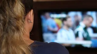 Una mujer viendo un partido de fútbol en una televisión