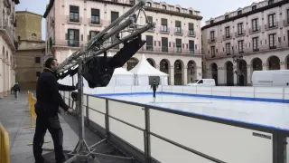 Un operario descarga materiales para la pista de hielo natural instalada en la plaza del Mercado de Huesca.