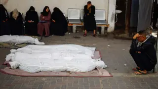 People mourn next to bodies of Palestinians killed in Israeli strikes, in Rafah