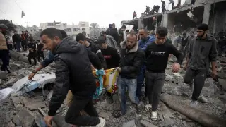 Palestinos cargan a una persona muerta que fue encontrada bajo los escombros de un edificio destruido tras los ataques aéreos israelíes en el campo de refugiados de Khan Younis, en el sur de la Franja de Gaza