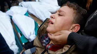 Un niño herido por los bombardeos israelíe sloora desoconsolado ante lcadáveres de sus familiares en el hospital Nasser de Jan Yunis en Gaza.