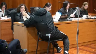 El acusado, de espaldas, toma notas delante de su abogada defensora, Elena Carnicer.