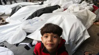 A boy looks on next to the bodies of Palestinians killed in Israeli strikes, at a hospital in Rafah