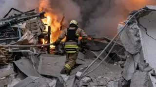 Un bombero ucraniano trata de apagar un fuego en un edificio bombardeado por Rusia en la ciudad de Kharkiv.