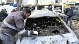 Miembros de protección civil inspeccionan algunos vehículos afectados por las explosiones en Beirut.