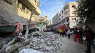 Varios palestinos buscan entre los escombros tras un bombardeo en un campo de refugiados en el centro de Gaza.