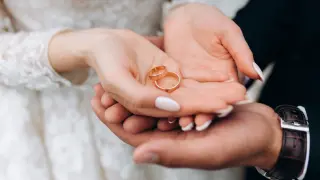 Groom holds bride's hands, where are two wedding rings